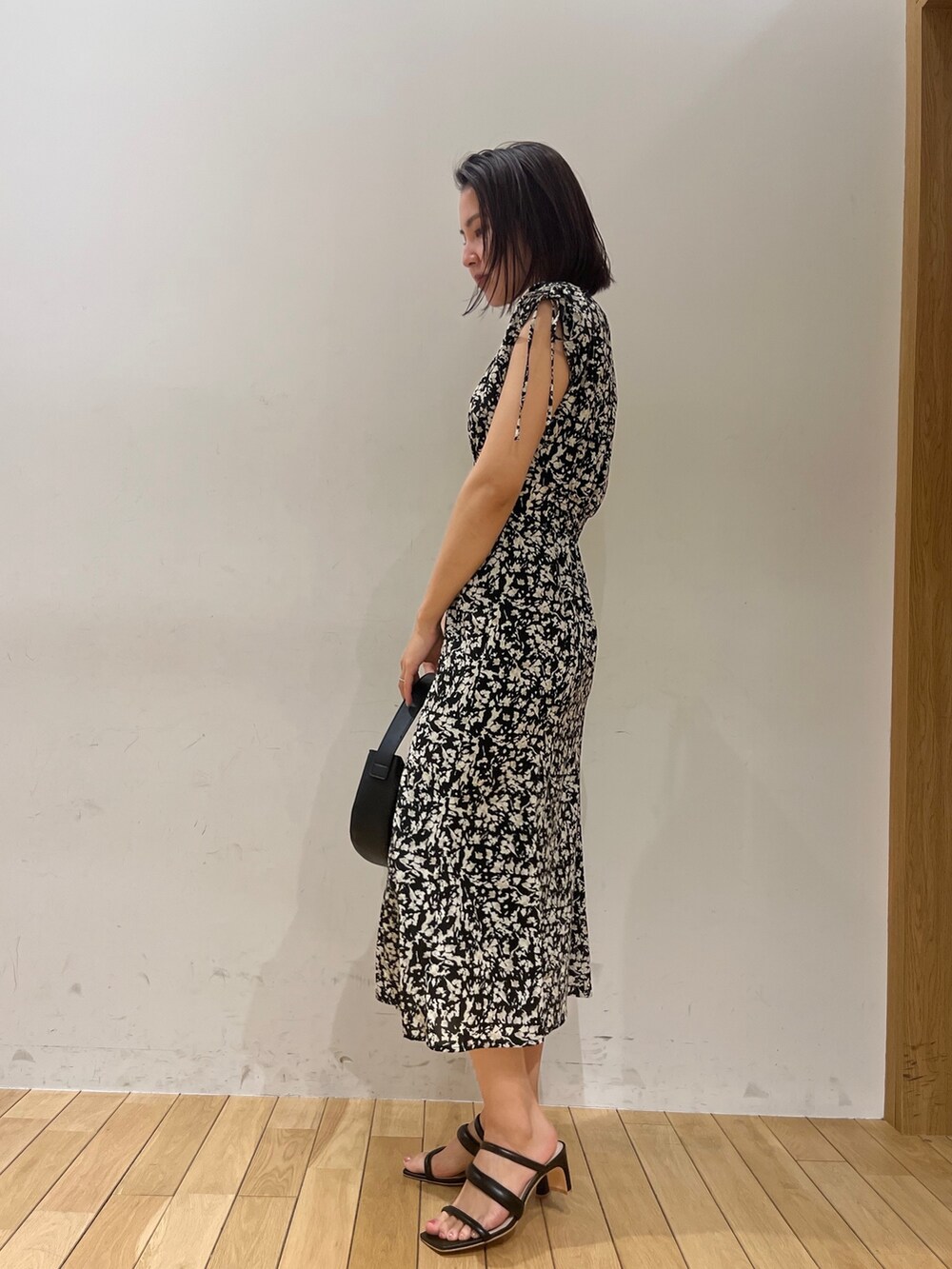 ブラック系のワンピース、ブラック系のハンドバッグ、ブラック系のサンダルを着用したレディースの春コーディネートの2枚目の写真