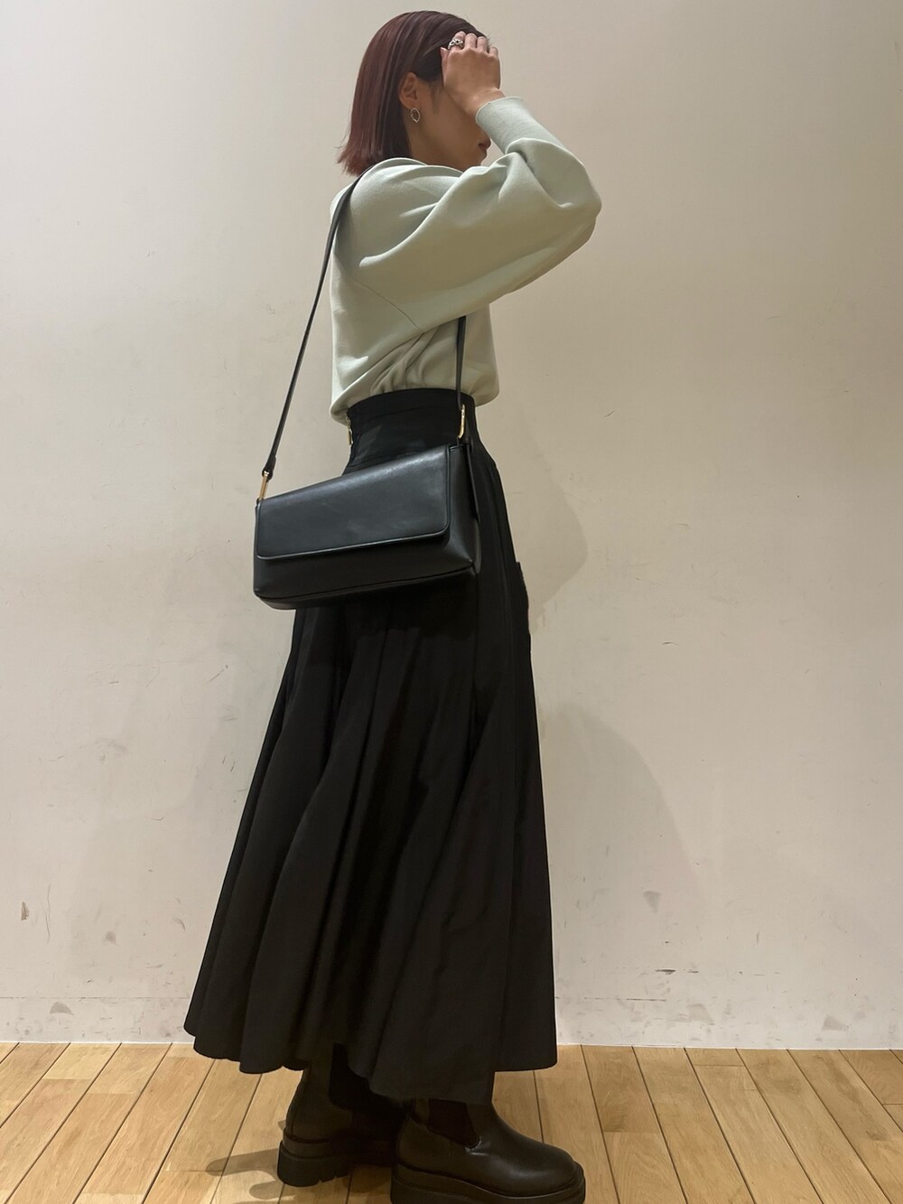 ブラック系のブーツ、ブラック系のスカート、グリーン系のニット/セーターを着用したレディースの冬コーディネートの2枚目の写真