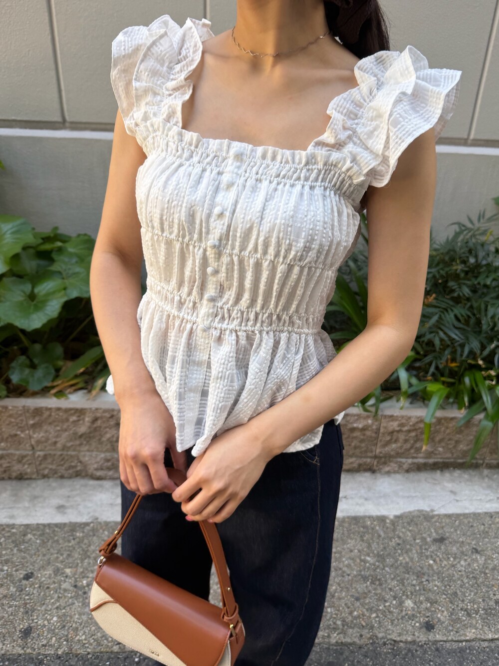 ブルー系のデニムパンツ、ブラウン系のハンドバッグ、ホワイト系のシャツ/ブラウスを着用したレディースの春コーディネートの7枚目の写真
