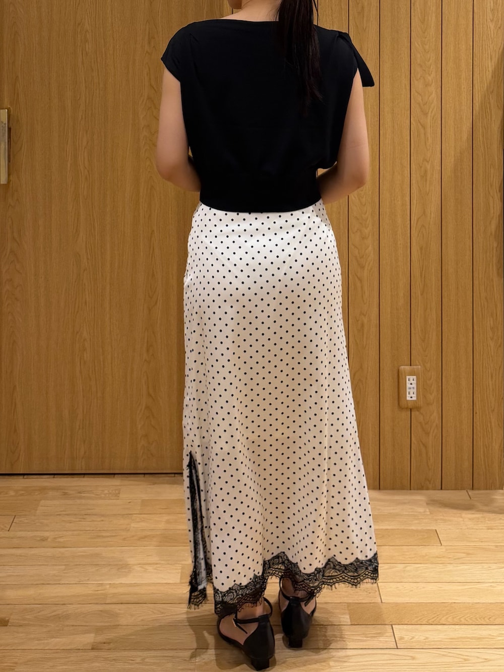 ブラック系のパンプス、ブラック系のニット/セーター、ホワイト系のスカートを着用したレディースの夏コーディネートの3枚目の写真