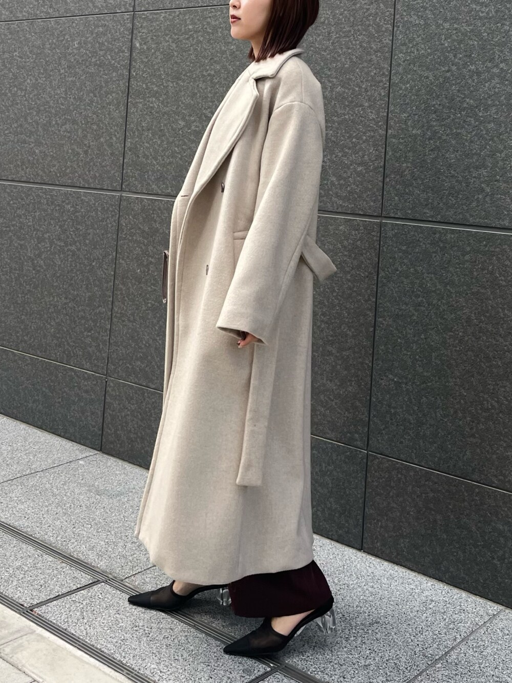 レッド系のパンツドレス、ホワイト系のチェスターコートを着用したレディースの冬コーディネートの2枚目の写真