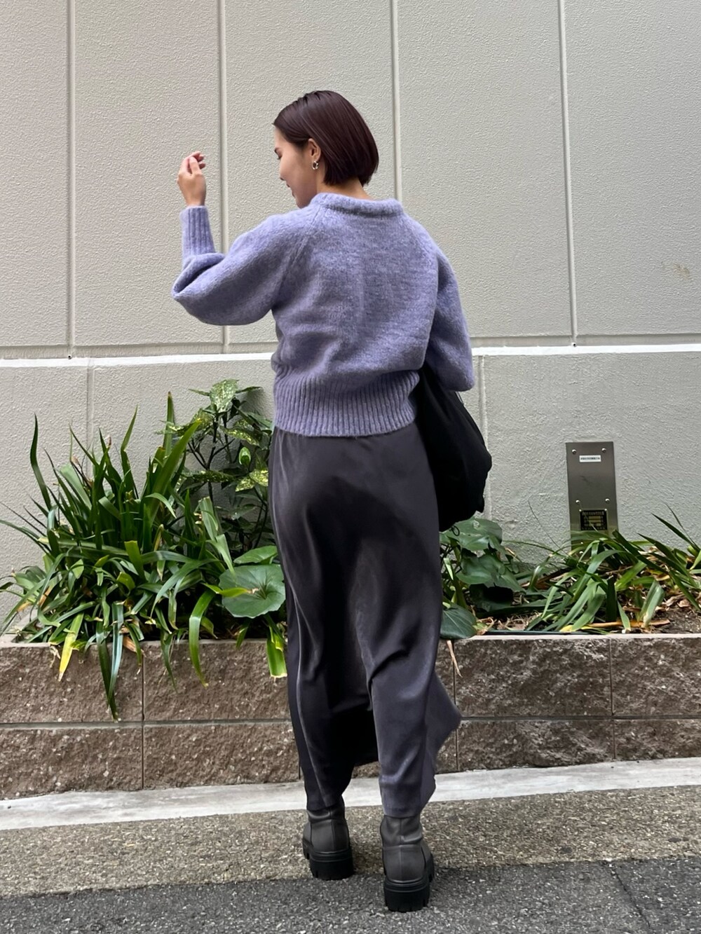 グレー系のスカート、パープル系のニット/セーター、ブラック系のダウンジャケット/コートを着用したレディースの冬コーディネートの3枚目の写真