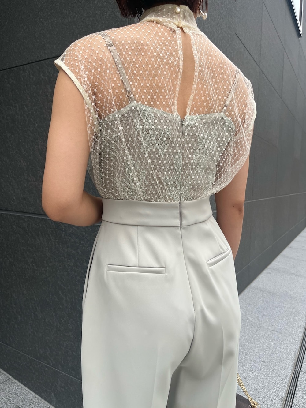 シルバー系のハンドバッグ、シルバー系のパンプス、グリーン系のパンツドレスを着用したレディースの春コーディネートの6枚目の写真