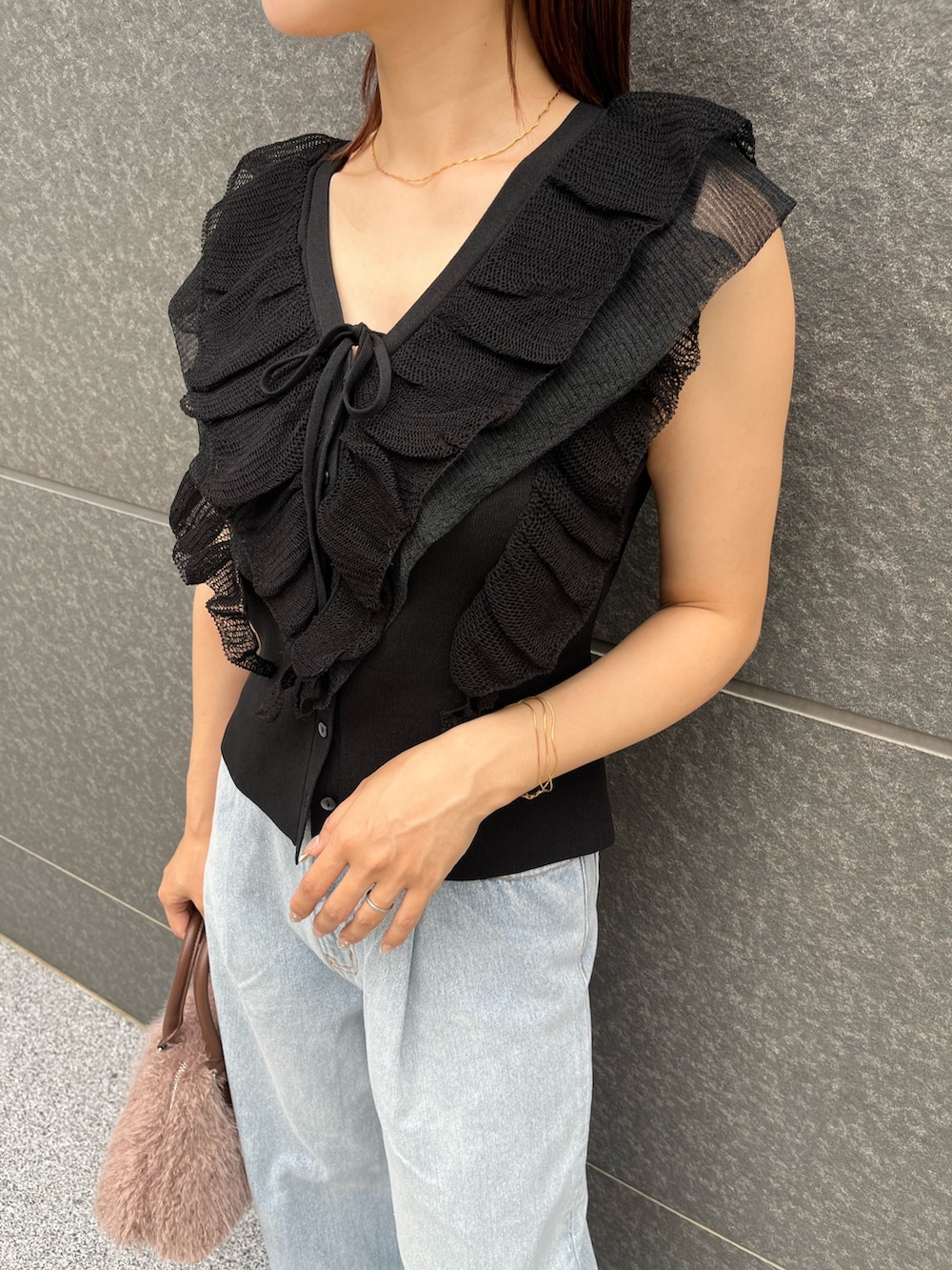 ブラック系のニット/セーター、ブルー系のデニムパンツ、ベージュ系のボストンバッグを着用したレディースの夏コーディネートの7枚目の写真