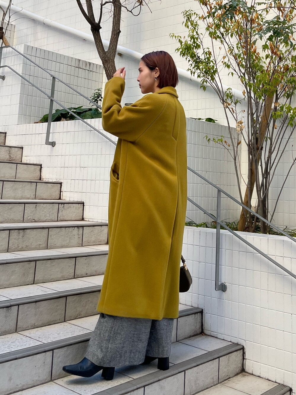 グリーン系のチェスターコート、ブラック系のその他パンツ、ブラック系のニット/セーターを着用したレディースの冬コーディネートの3枚目の写真