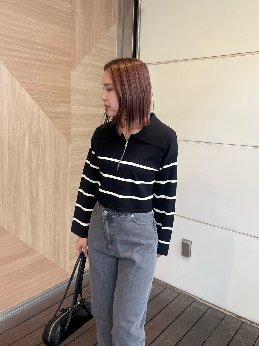 ブラック系のデニムパンツ、ブラック系のニット/セーター、ブラック系のショルダーバッグを着用したレディースの冬コーディネートの4枚目の写真