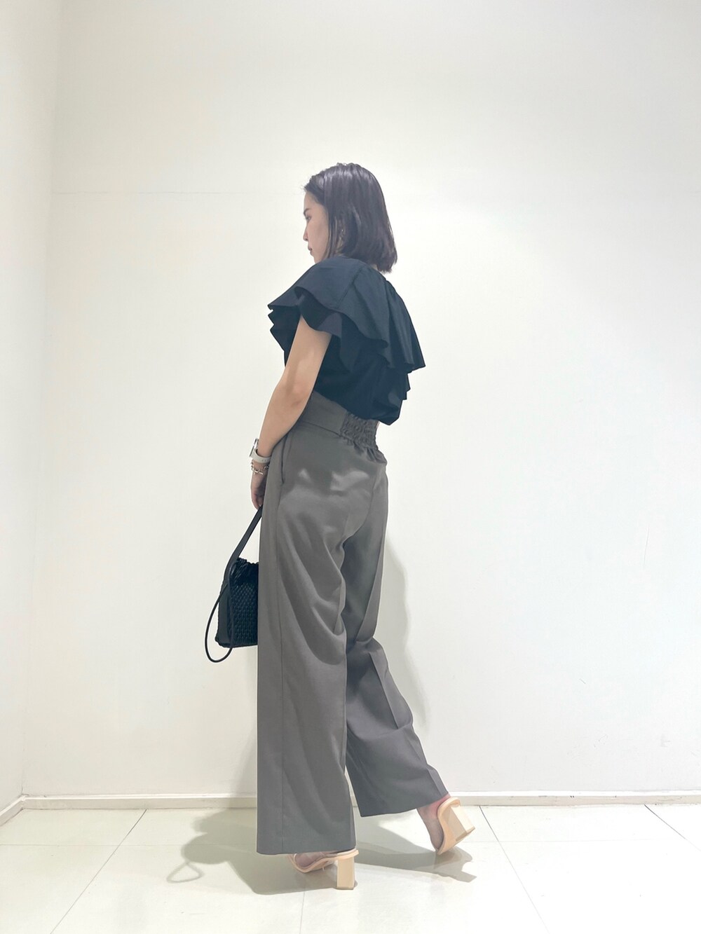 ベージュ系のスラックス、ブラック系のシャツ/ブラウスを着用したレディースの夏コーディネートの3枚目の写真