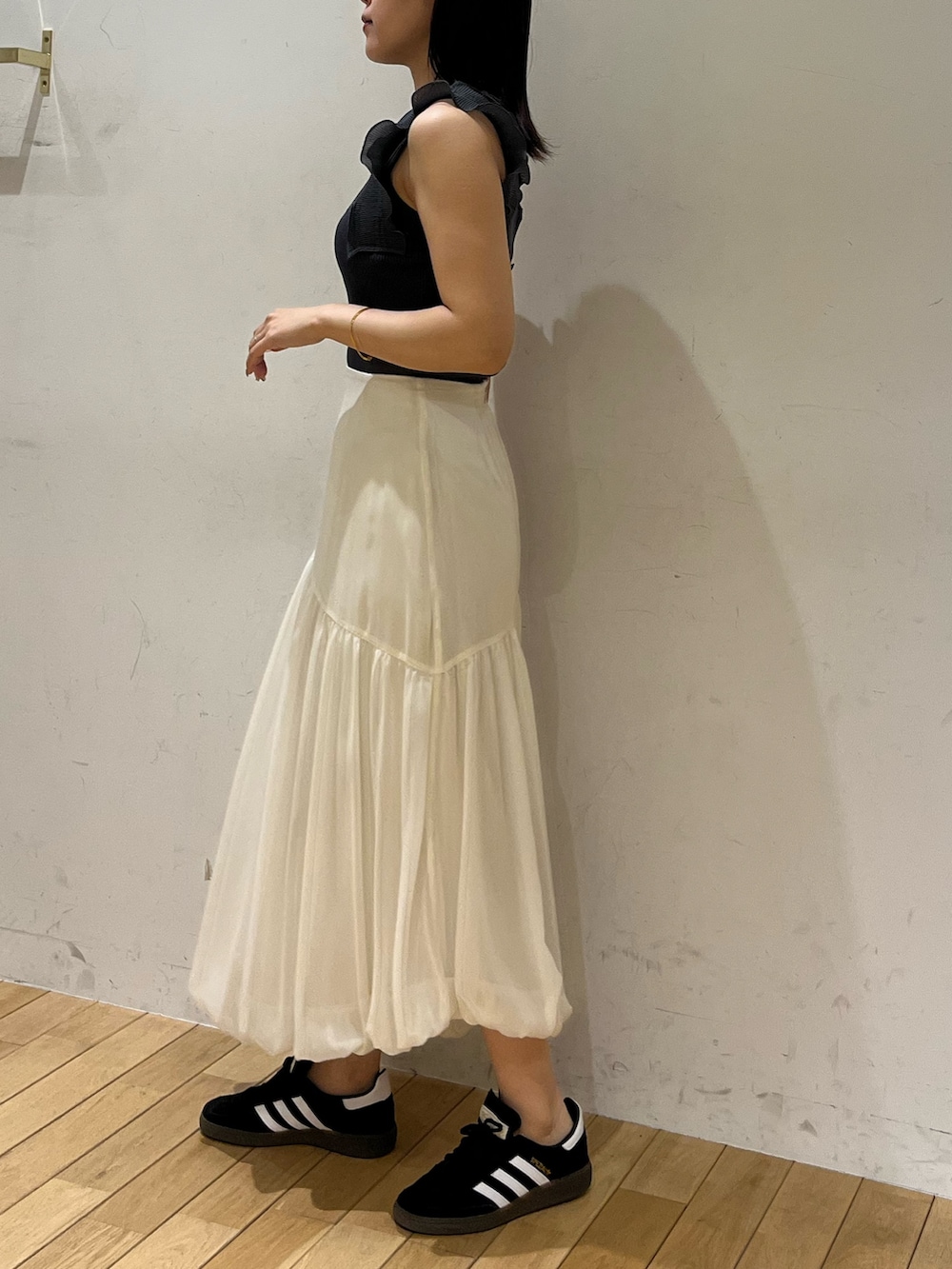 ブラック系のスニーカー、ホワイト系のスカート、グレー系のニット/セーターを着用したレディースの夏コーディネートの2枚目の写真