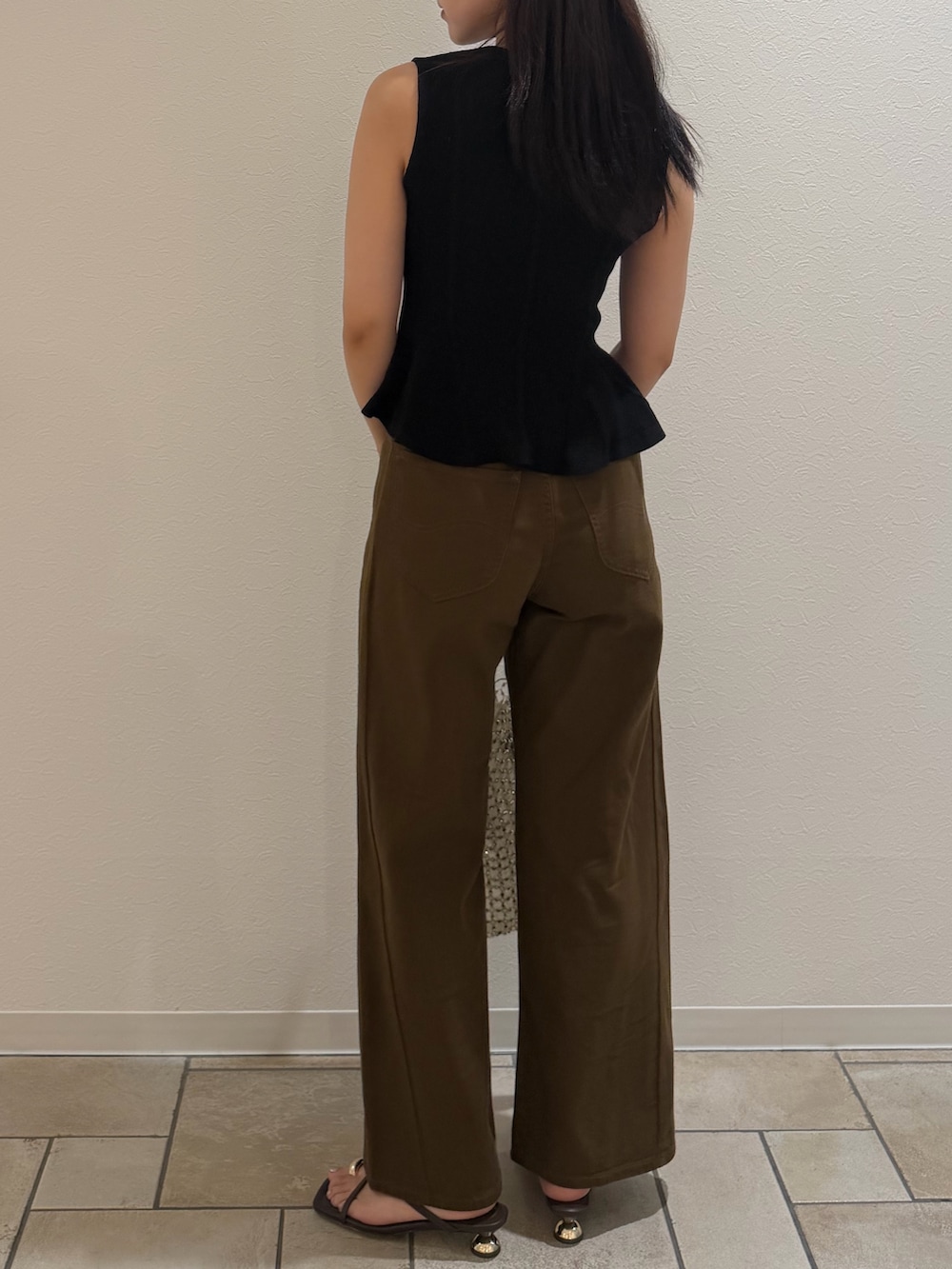 ブラック系のニット/セーター、ブラウン系のデニムパンツ、ブラウン系のサンダルを着用したレディースの夏コーディネートの3枚目の写真