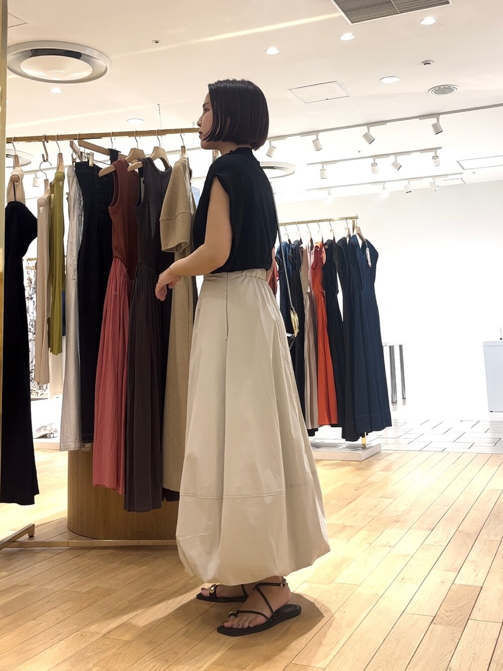 ホワイト系のスカート、ブラック系のサンダル、ブラック系のショルダーバッグを着用したレディースの夏コーディネートの2枚目の写真