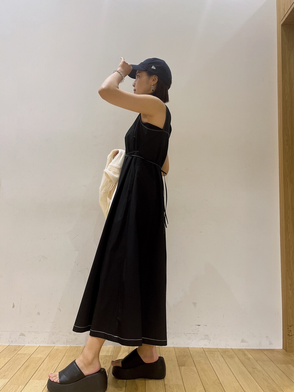 ベージュ系のハンドバッグ、ブラック系のワンピースを着用したレディースの夏コーディネートの2枚目の写真