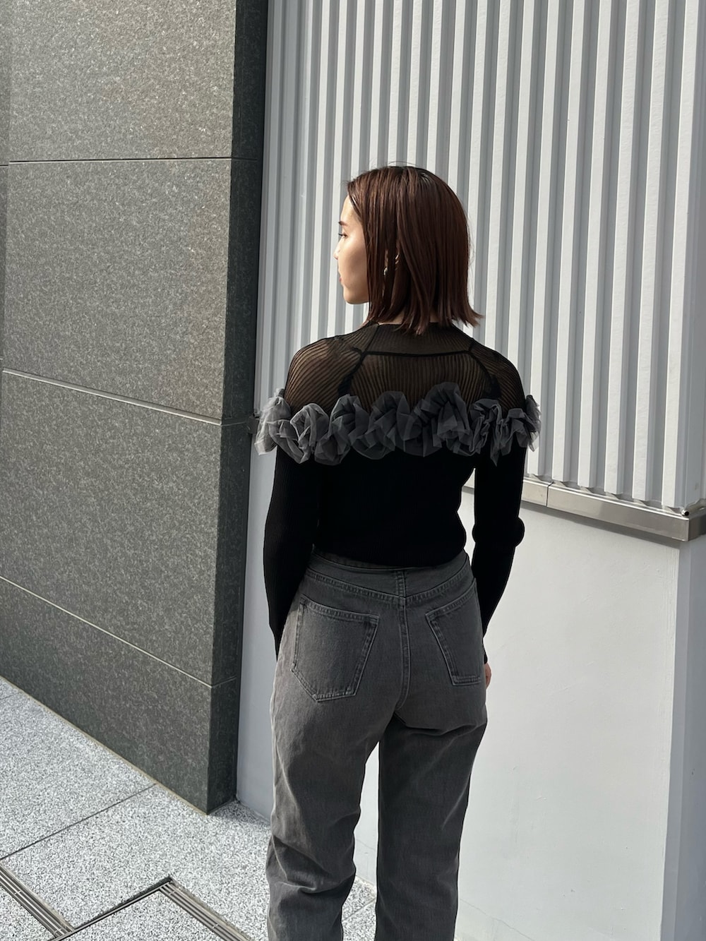 ブラック系のデニムパンツ、ブラック系のニット/セーターを着用したレディースの秋コーディネートの4枚目の写真