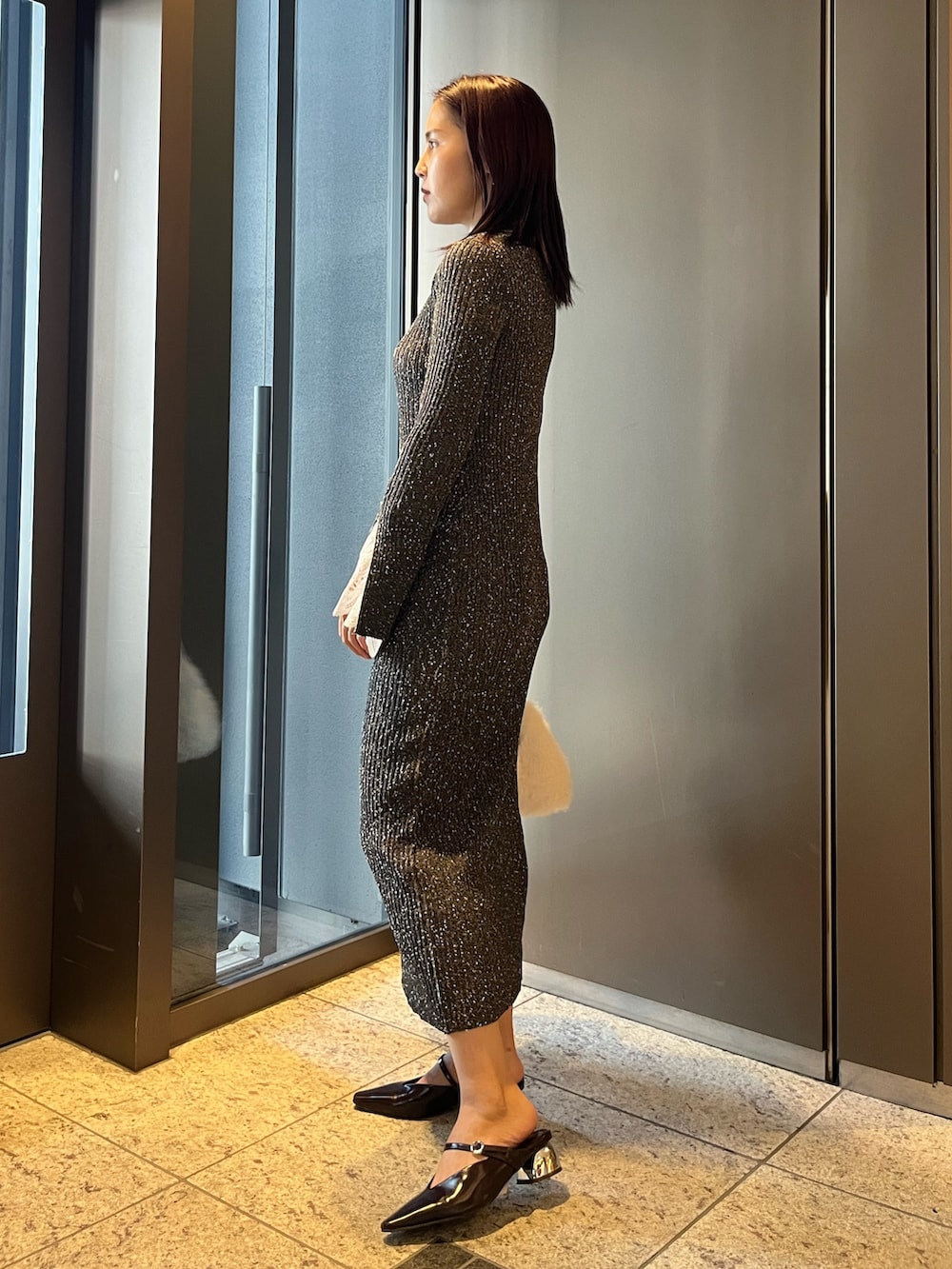 ホワイト系のボストンバッグ、ブラウン系のパンプス、グレー系のワンピースを着用したレディースの夏コーディネートの2枚目の写真