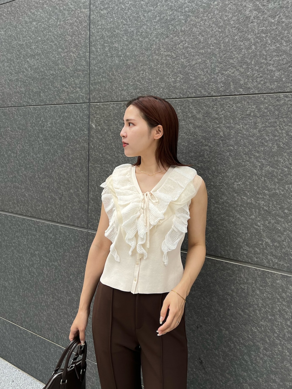 ホワイト系のニット/セーター、ブラウン系のその他パンツ、ブラウン系のボストンバッグを着用したレディースの夏コーディネートの5枚目の写真