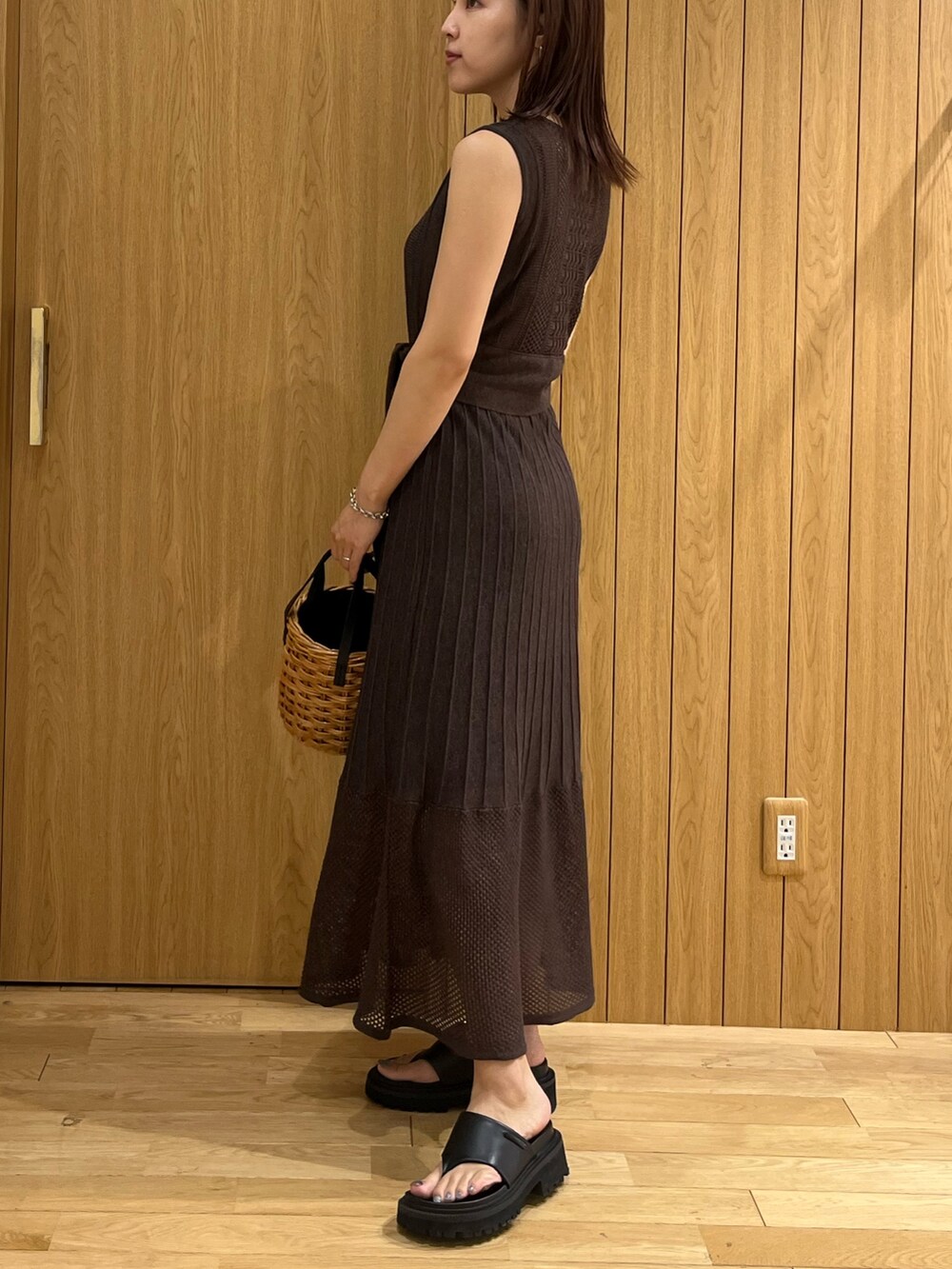 ブラウン系のハンドバッグ、ブラウン系のワンピース、シルバー系のネックレスを着用したレディースの夏コーディネートの2枚目の写真