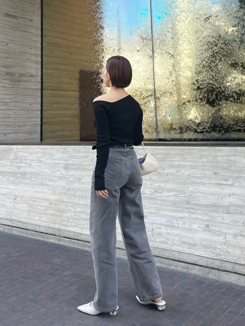 グレー系のデニムパンツ、ブラック系のニット/セーター、ブラック系のベルトを着用したレディースの春コーディネートの3枚目の写真