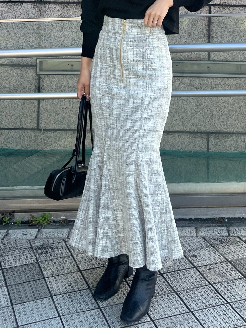 ホワイト系のスカート、ブラック系のニット/セーター、ブラック系のショルダーバッグを着用したレディースの冬コーディネートの4枚目の写真