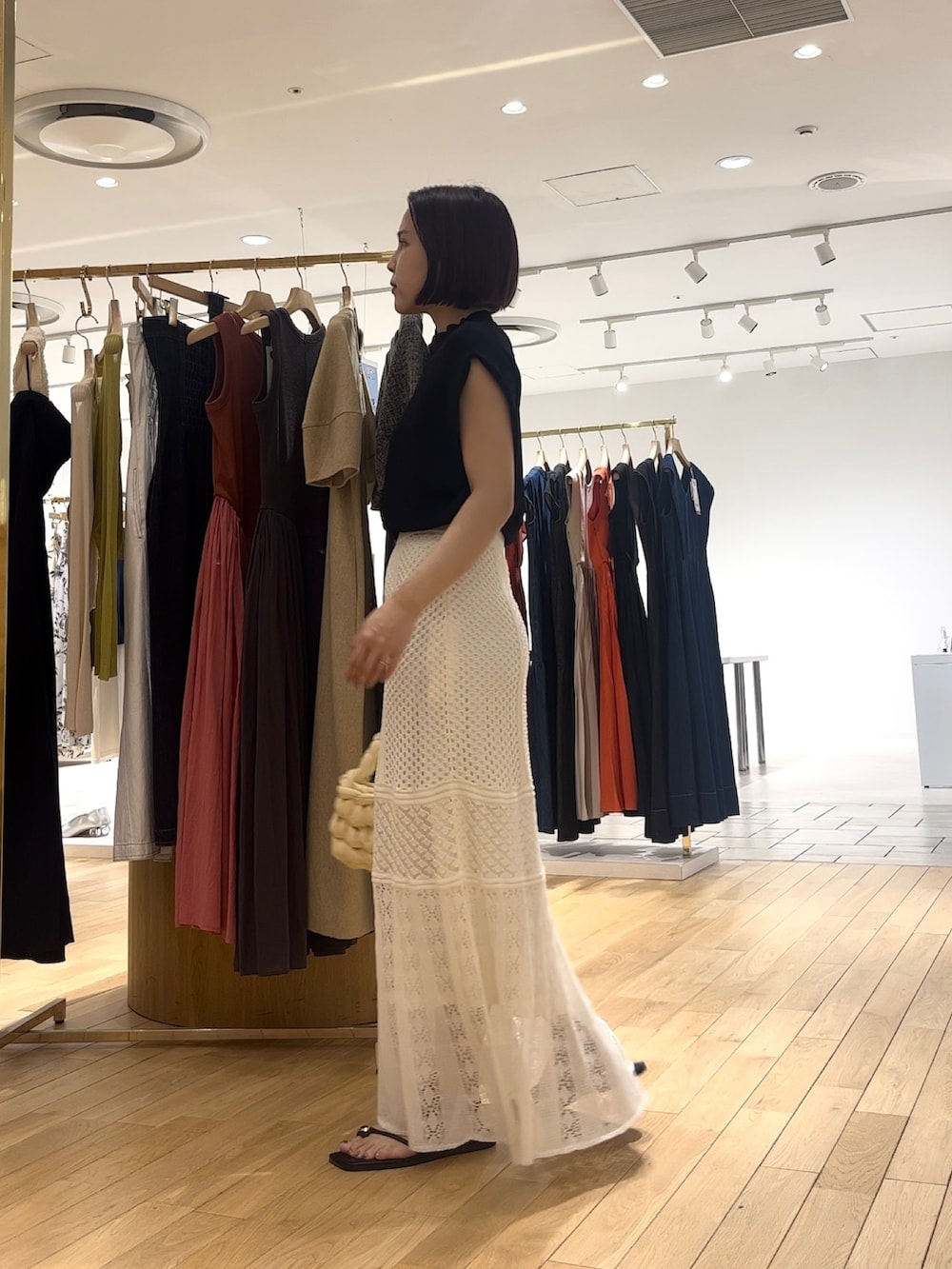 ホワイト系のスカート、ブラック系のサンダル、ホワイト系のハンドバッグを着用したレディースの夏コーディネートの2枚目の写真