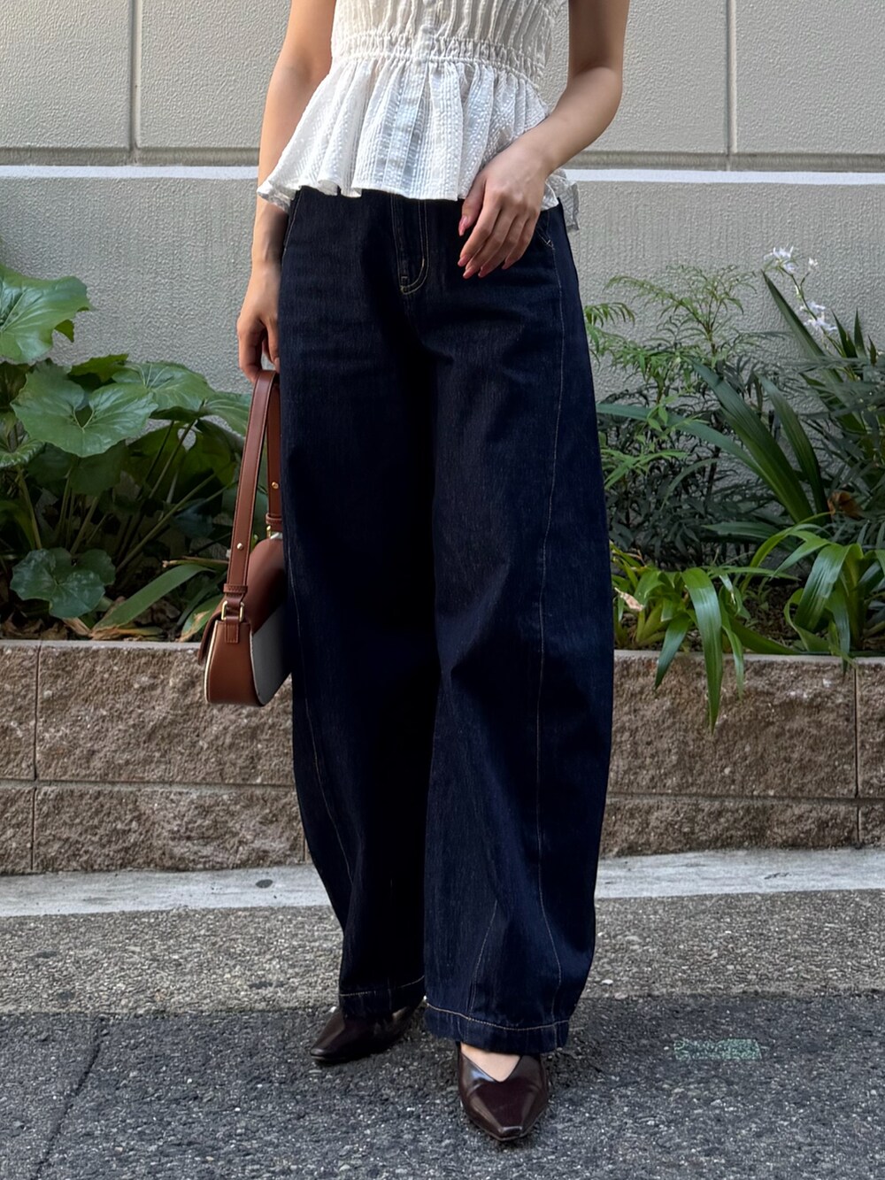 ブルー系のデニムパンツ、ブラウン系のハンドバッグ、ホワイト系のシャツ/ブラウスを着用したレディースの春コーディネートの4枚目の写真