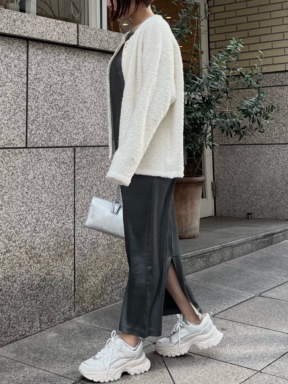 シルバー系のハンドバッグ、ホワイト系のスニーカー、グレー系のワンピースを着用したレディースの春コーディネートの3枚目の写真