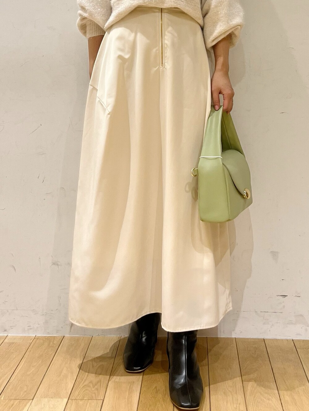 ホワイト系のスカート、ホワイト系のカーディガン/ボレロ、グリーン系のハンドバッグを着用したレディースの秋コーディネートの2枚目の写真