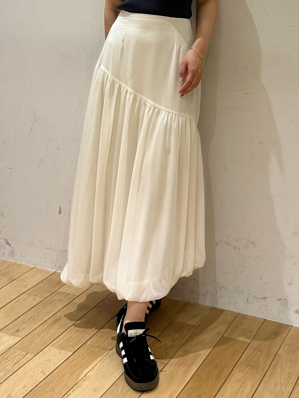 ブラック系のスニーカー、ホワイト系のスカート、グレー系のニット/セーターを着用したレディースの夏コーディネートの4枚目の写真