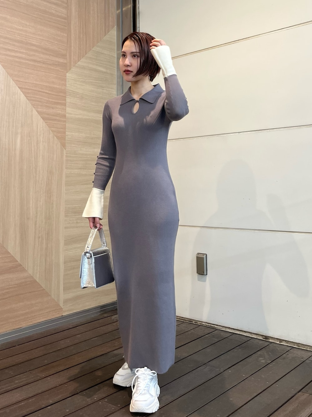 グレー系のワンピース、ホワイト系のスニーカー、シルバー系のショルダーバッグを着用したレディースの冬コーディネートの2枚目の写真