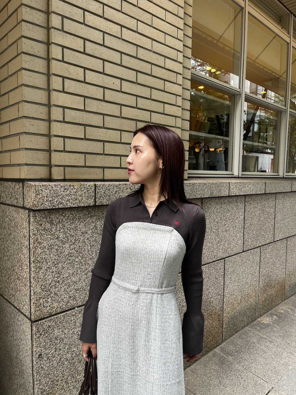 グレー系のワンピース、ブラウン系のボストンバッグ、ブラック系のブーツを着用したレディースの秋コーディネートの4枚目の写真