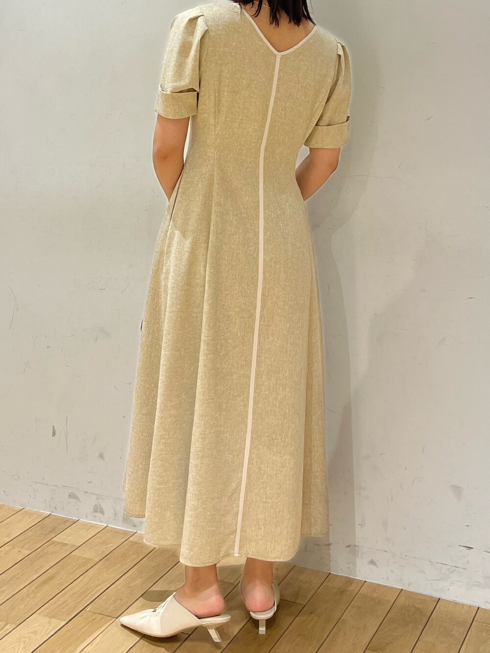 ベージュ系のワンピース、ホワイト系のサンダル、ブラック系のハンドバッグを着用したレディースの春コーディネートの3枚目の写真