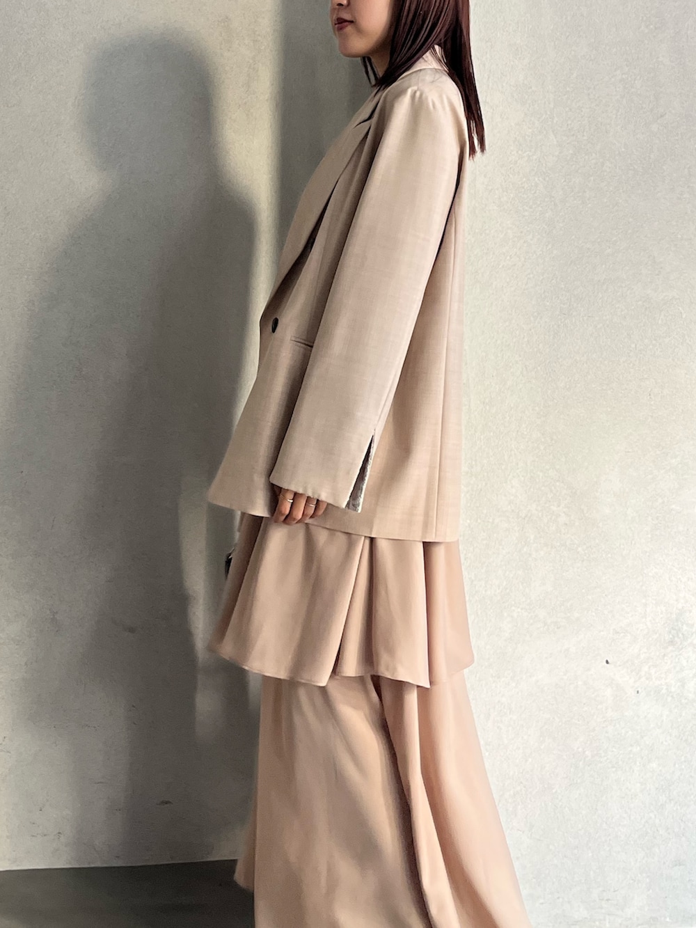 ベージュ系のテーラードジャケット、ベージュ系のワンピース、ブラウン系のハンドバッグを着用したレディースの冬コーディネートの6枚目の写真