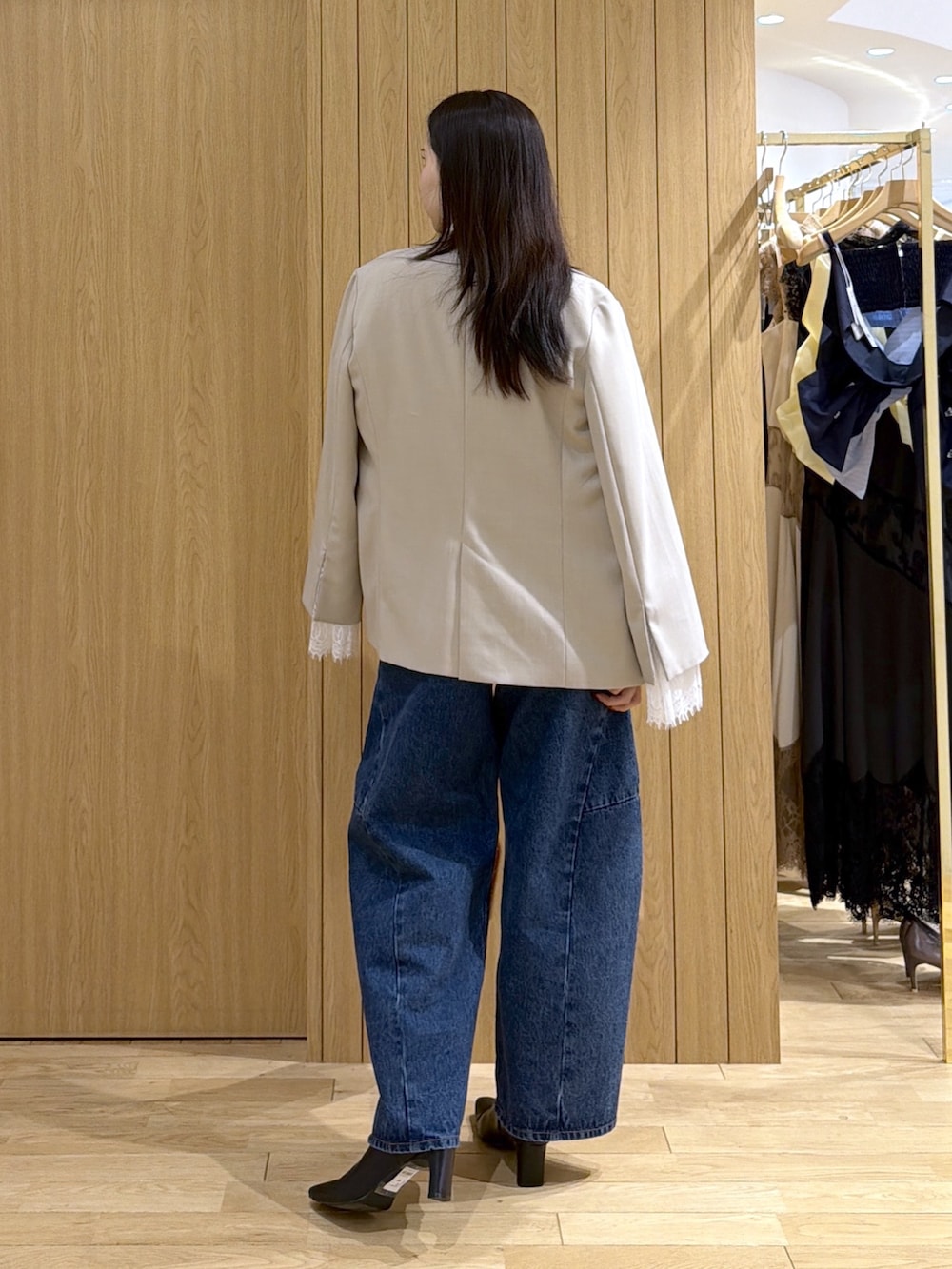 ブルー系のデニムパンツ、レッド系のハンドバッグ、ブラック系のブーツを着用したレディースの秋コーディネートの3枚目の写真