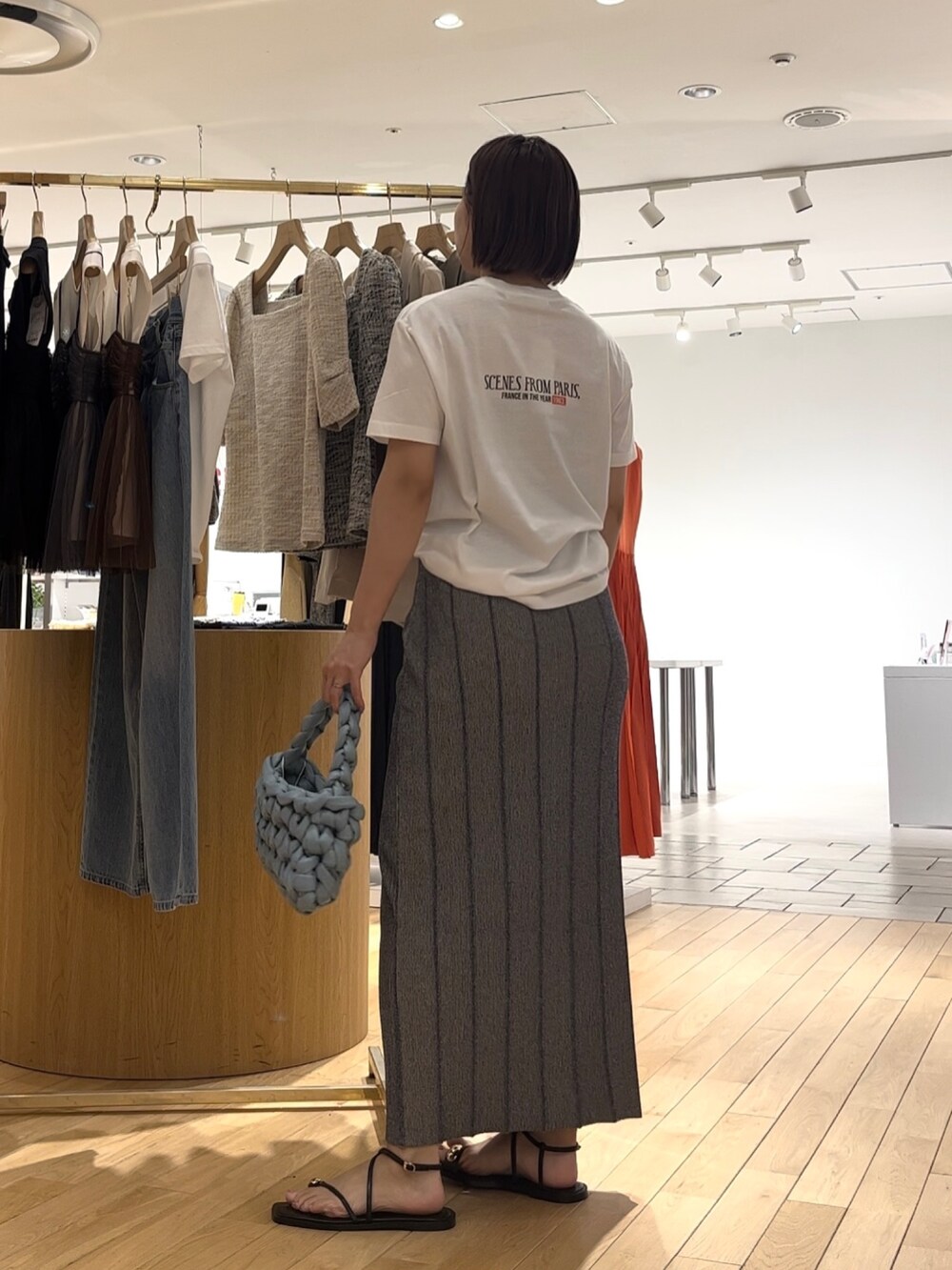 グレー系のスカート、ブラック系のサンダル、ブルー系のハンドバッグを着用したレディースの夏コーディネートの3枚目の写真