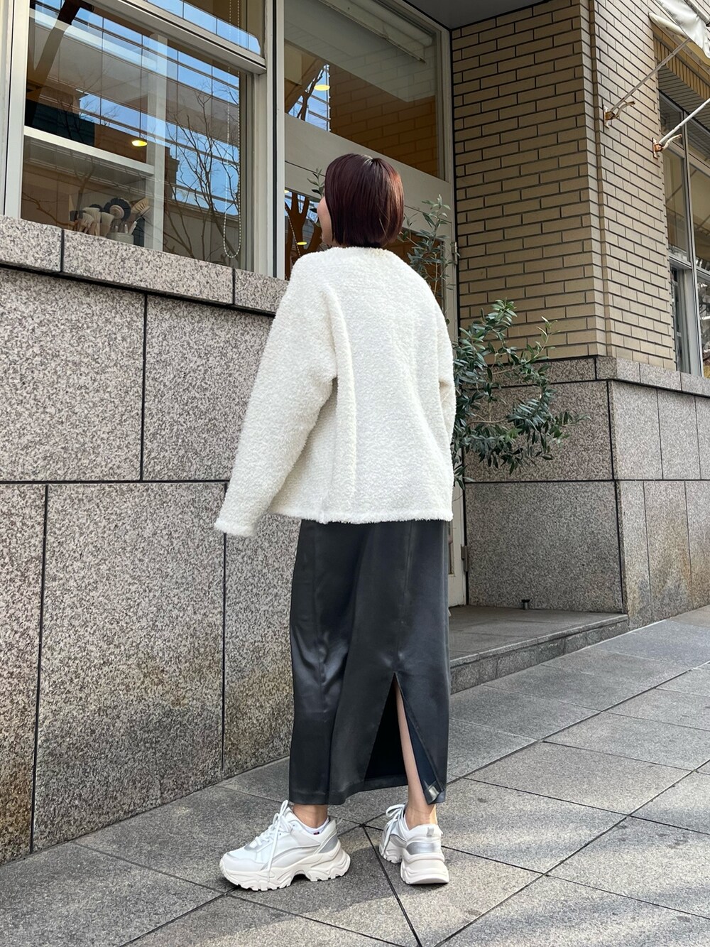 シルバー系のハンドバッグ、ホワイト系のスニーカー、グレー系のワンピースを着用したレディースの春コーディネートの4枚目の写真