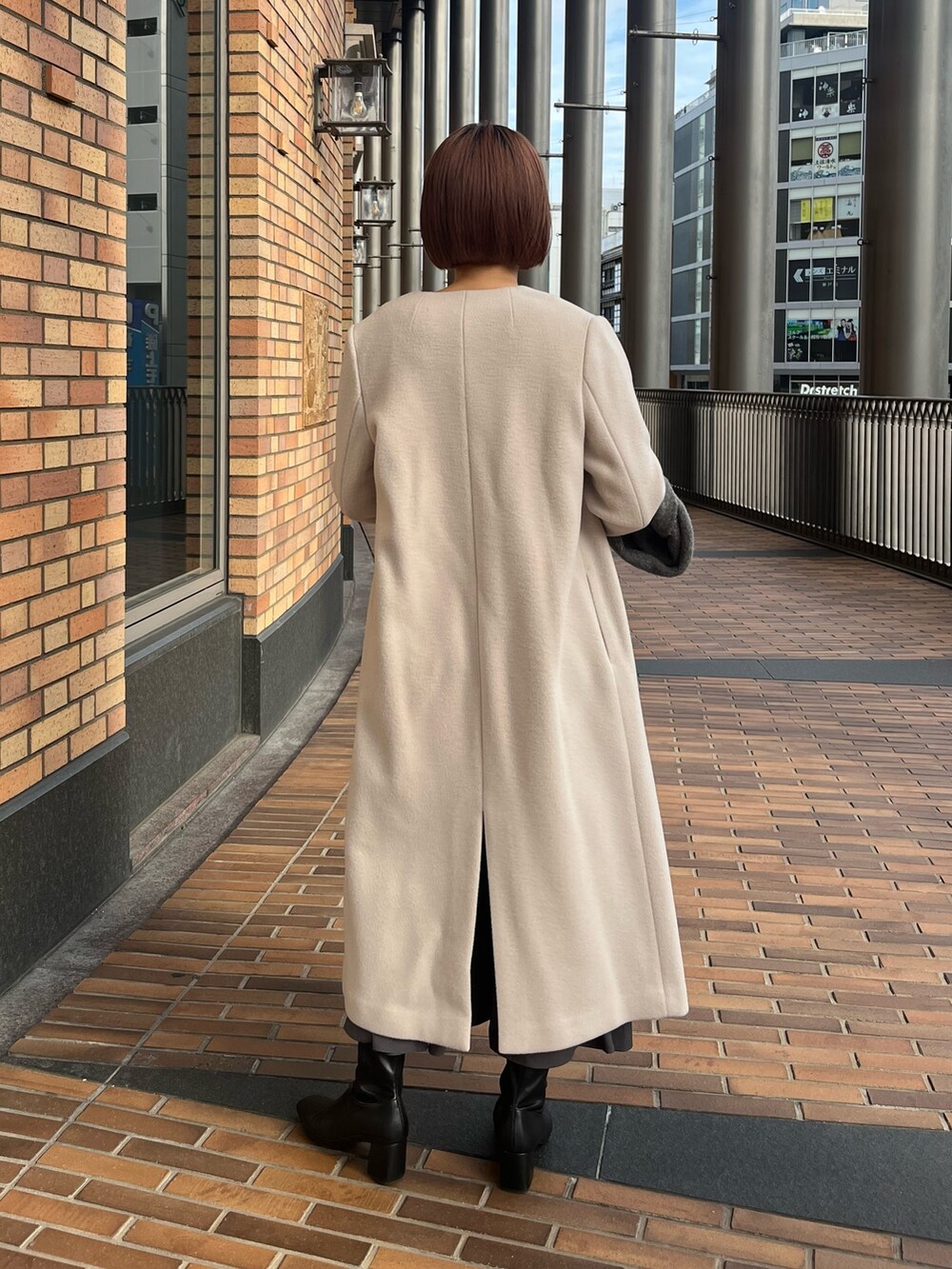 ホワイト系のノーカラーコート、ブラック系のワンピース、グレー系のショルダーバッグを着用したレディースの冬コーディネートの4枚目の写真