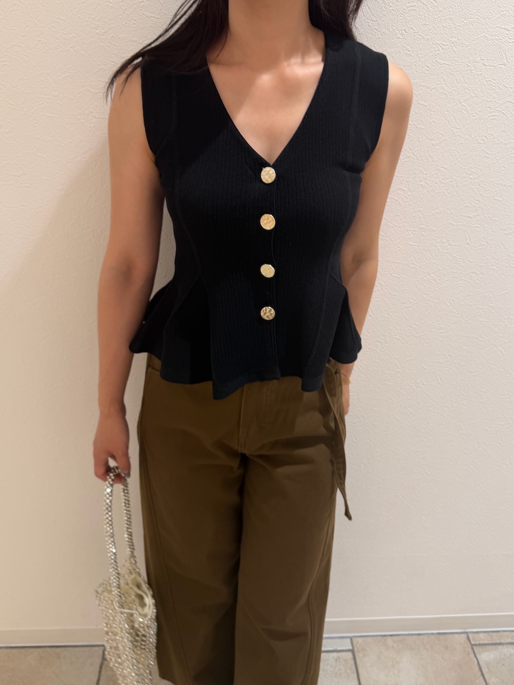 ブラック系のニット/セーター、ブラウン系のデニムパンツ、ブラウン系のサンダルを着用したレディースの夏コーディネートの6枚目の写真