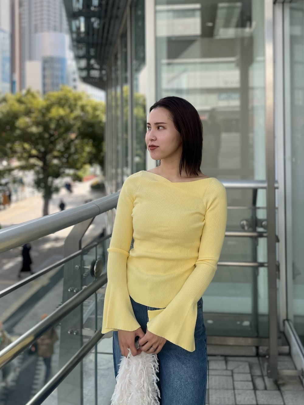 ブルー系のデニムパンツ、イエロー系のニット/セーター、ホワイト系のハンドバッグを着用したレディースの冬コーディネートの5枚目の写真