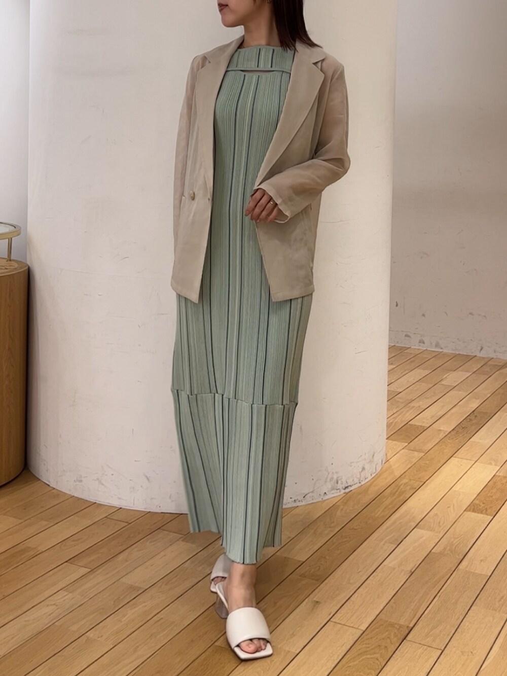 ホワイト系のサンダル、ホワイト系のテーラードジャケット、グリーン系のワンピースを着用したレディースの春コーディネートの6枚目の写真