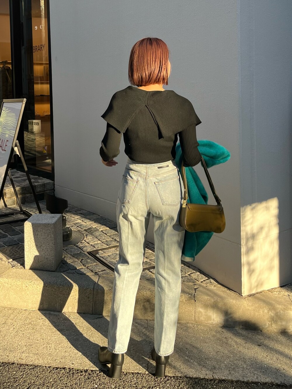 ブルー系のデニムパンツ、ブルー系のカーディガン/ボレロ、ブラック系のニット/セーターを着用したレディースの冬コーディネートの5枚目の写真