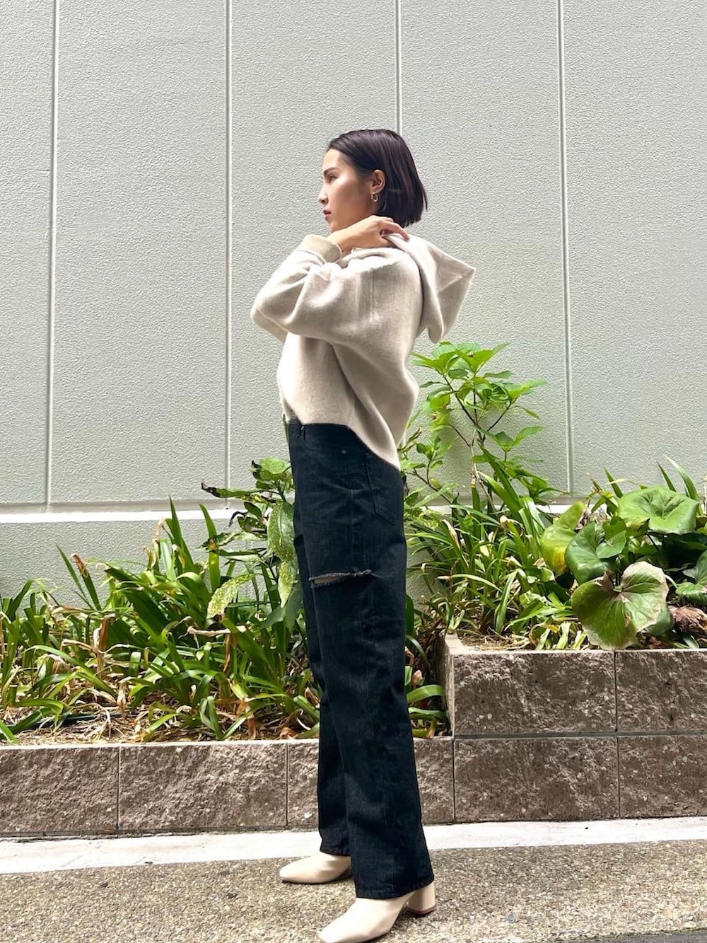 ホワイト系のブーツ、ブラック系のデニムパンツ、グリーン系のハンドバッグを着用したレディースの秋コーディネートの4枚目の写真