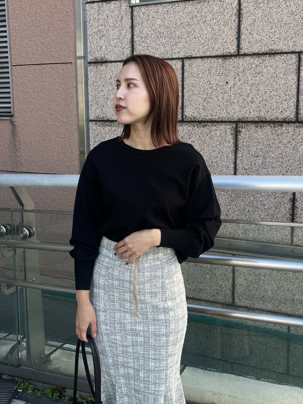 ホワイト系のスカート、ブラック系のニット/セーター、ブラック系のショルダーバッグを着用したレディースの冬コーディネートの5枚目の写真