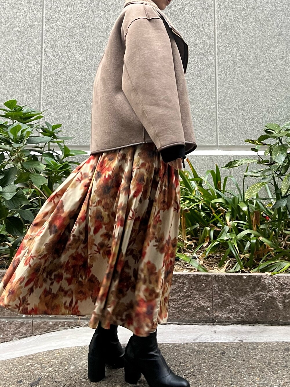 オレンジ系のスカート、ブラック系のニット/セーター、ベージュ系のムートンコートを着用したレディースの秋コーディネートの6枚目の写真