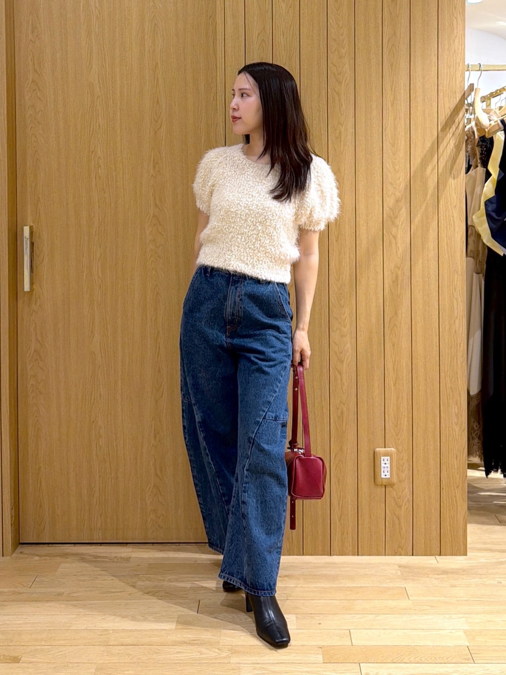ブルー系のデニムパンツ、レッド系のハンドバッグ、ブラック系のブーツを着用したレディースの秋コーディネートの4枚目の写真