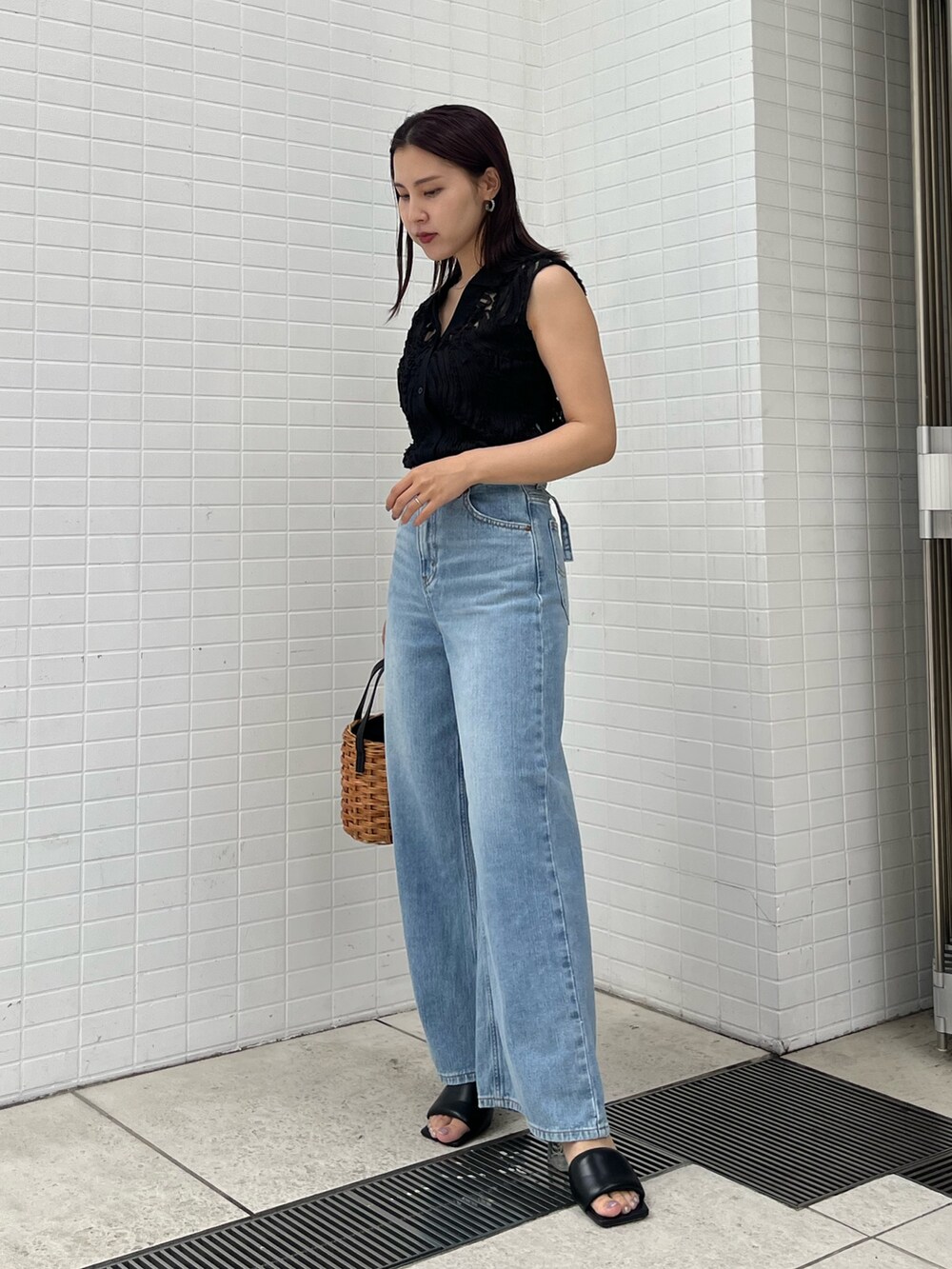 ブラウン系のハンドバッグ、ブラック系のサンダル、ブラック系のシャツ/ブラウスを着用したレディースの夏コーディネートの2枚目の写真