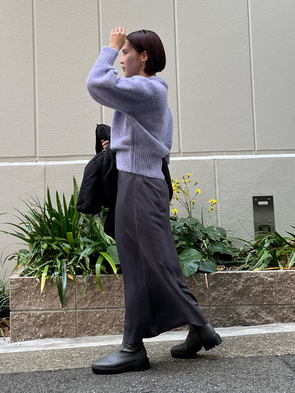 グレー系のスカート、パープル系のニット/セーター、ブラック系のダウンジャケット/コートを着用したレディースの冬コーディネートの2枚目の写真