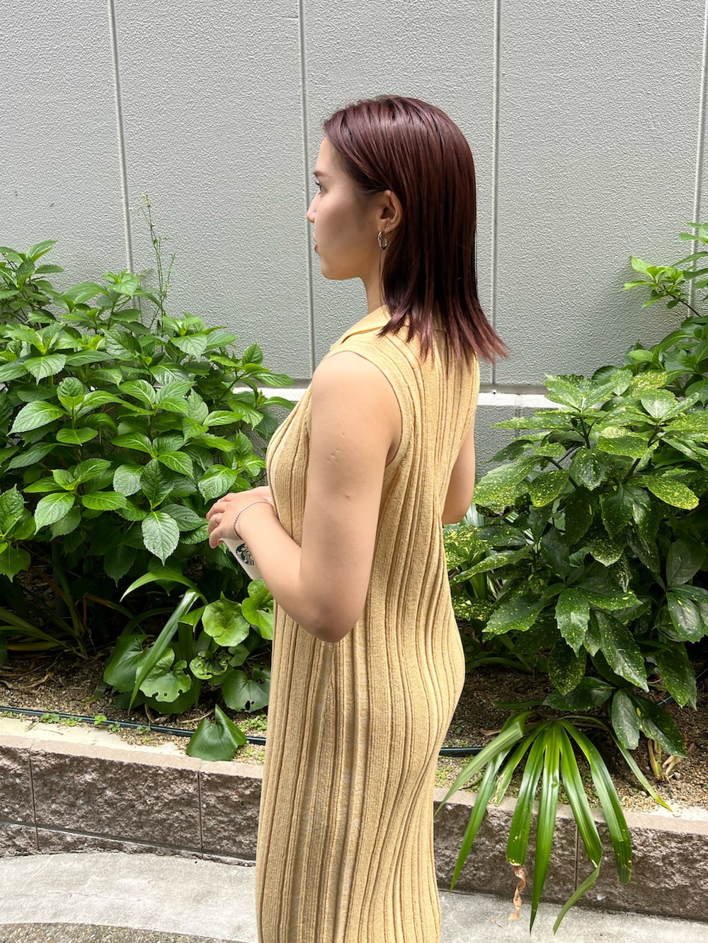 イエロー系のワンピース、ブラック系のハンドバッグ、ブラック系のサンダルを着用したレディースの夏コーディネートの6枚目の写真