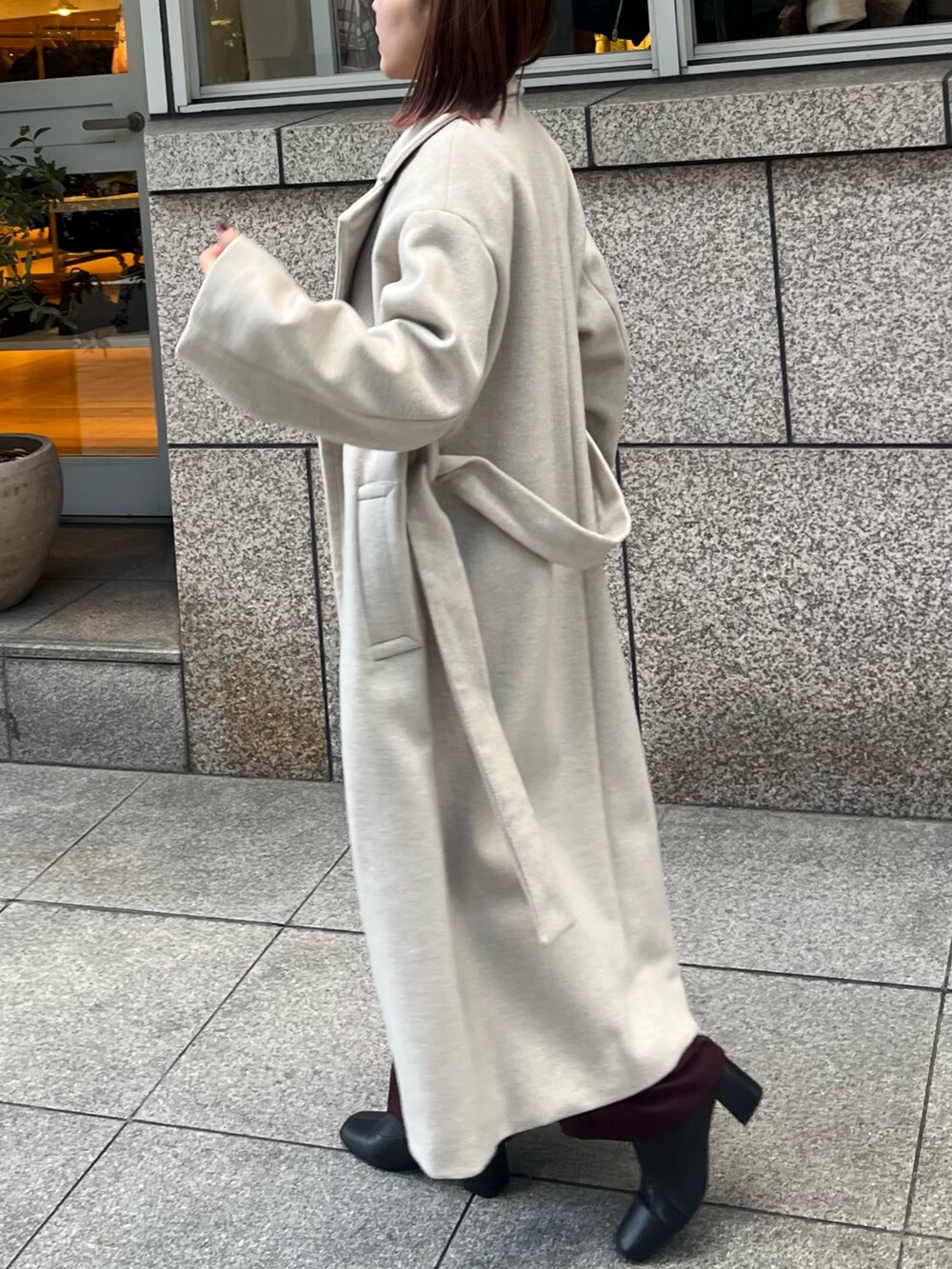 レッド系のパンツドレス、ホワイト系のチェスターコートを着用したレディースの冬コーディネートの5枚目の写真