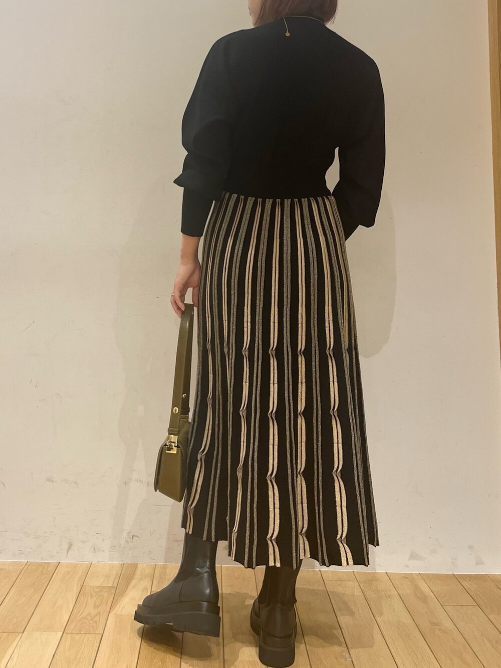 ブラック系のワンピース、ブラウン系のショルダーバッグ、ブラック系のダウンジャケット/コートを着用したレディースの秋コーディネートの4枚目の写真