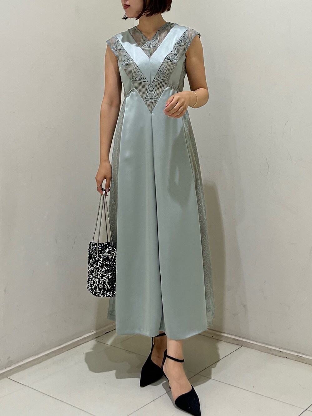 シルバー系のハンドバッグ、ブラック系のパンプス、グリーン系のドレスを着用したレディースの秋コーディネートの4枚目の写真