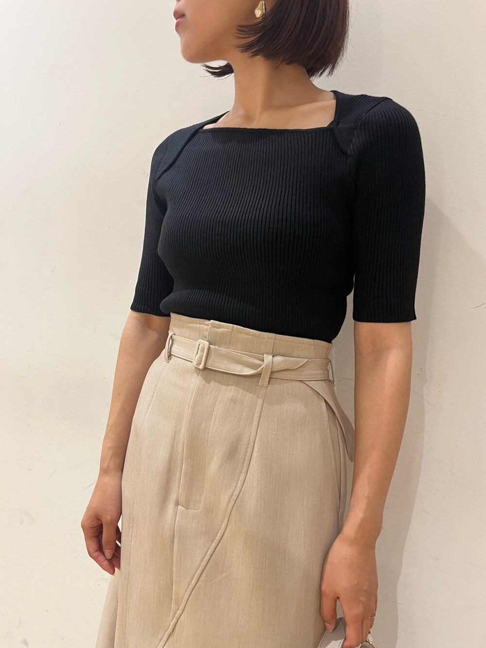 ベージュ系のスカート、ブラック系のニット/セーター、ホワイト系のハンドバッグを着用したレディースの夏コーディネートの3枚目の写真