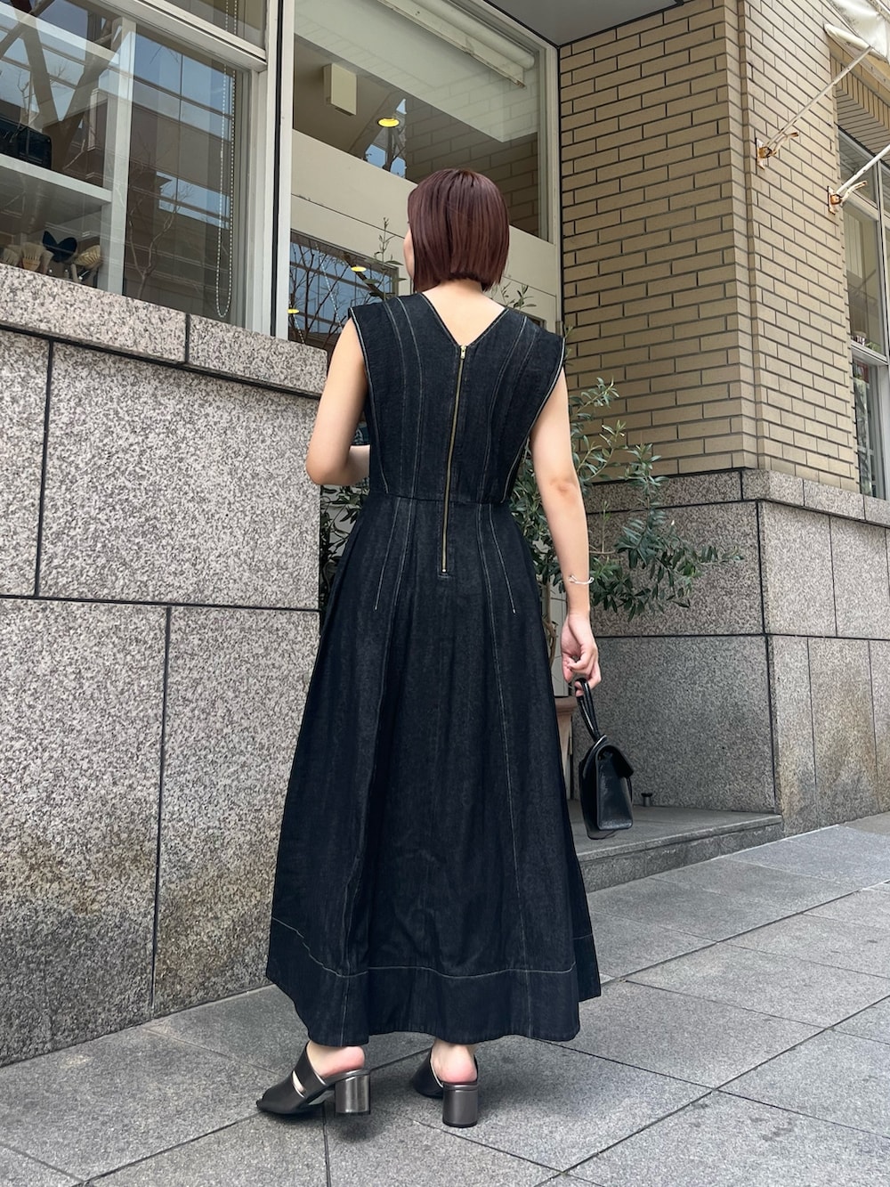 ブラック系のワンピース、その他のサンダル、ブラック系のハンドバッグを着用したレディースの春コーディネートの4枚目の写真